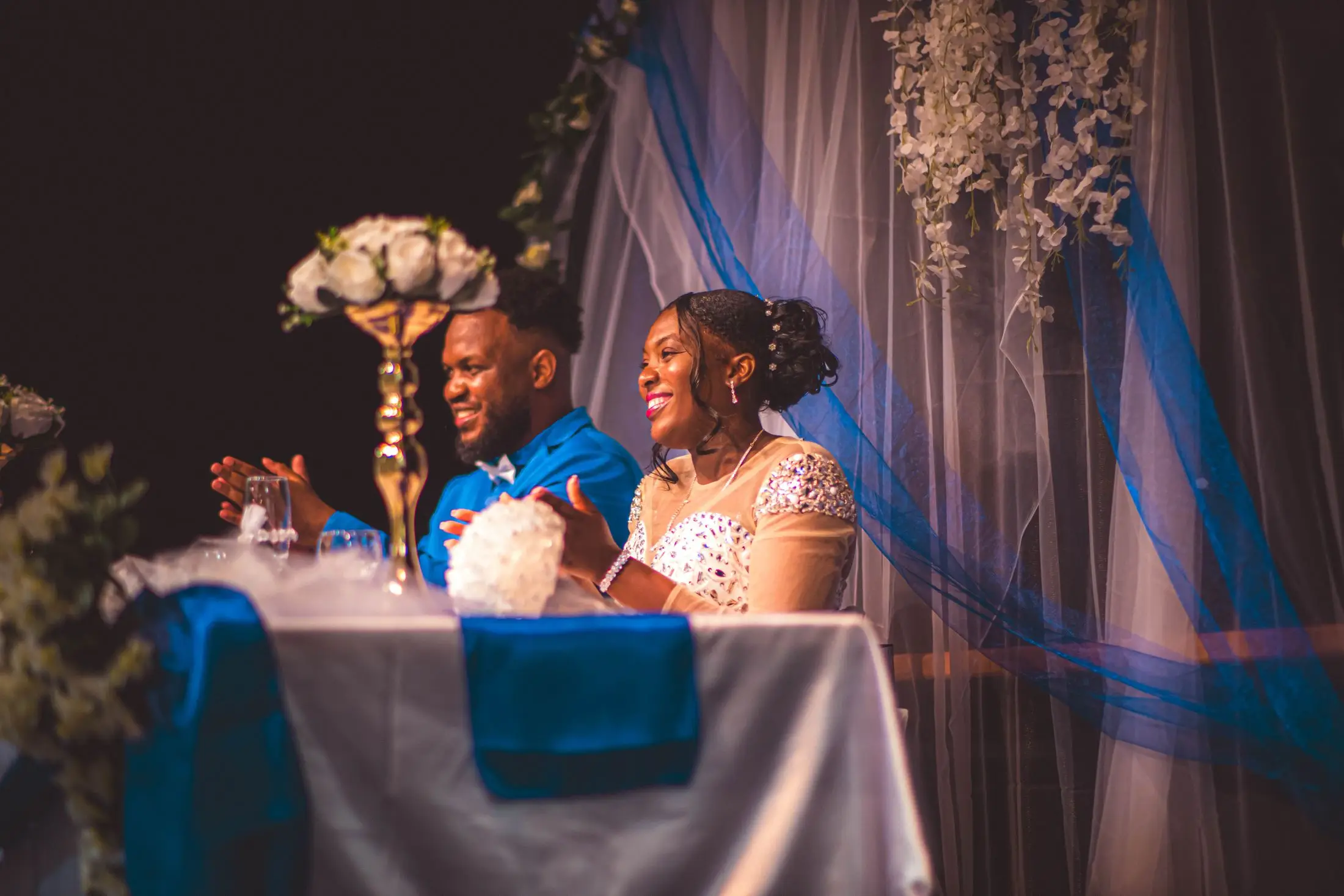 A smiling couple at their wedding head table